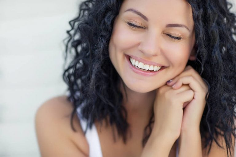 Woman with curly hair and youthful skin, symbolizing Juvéderm® filler results